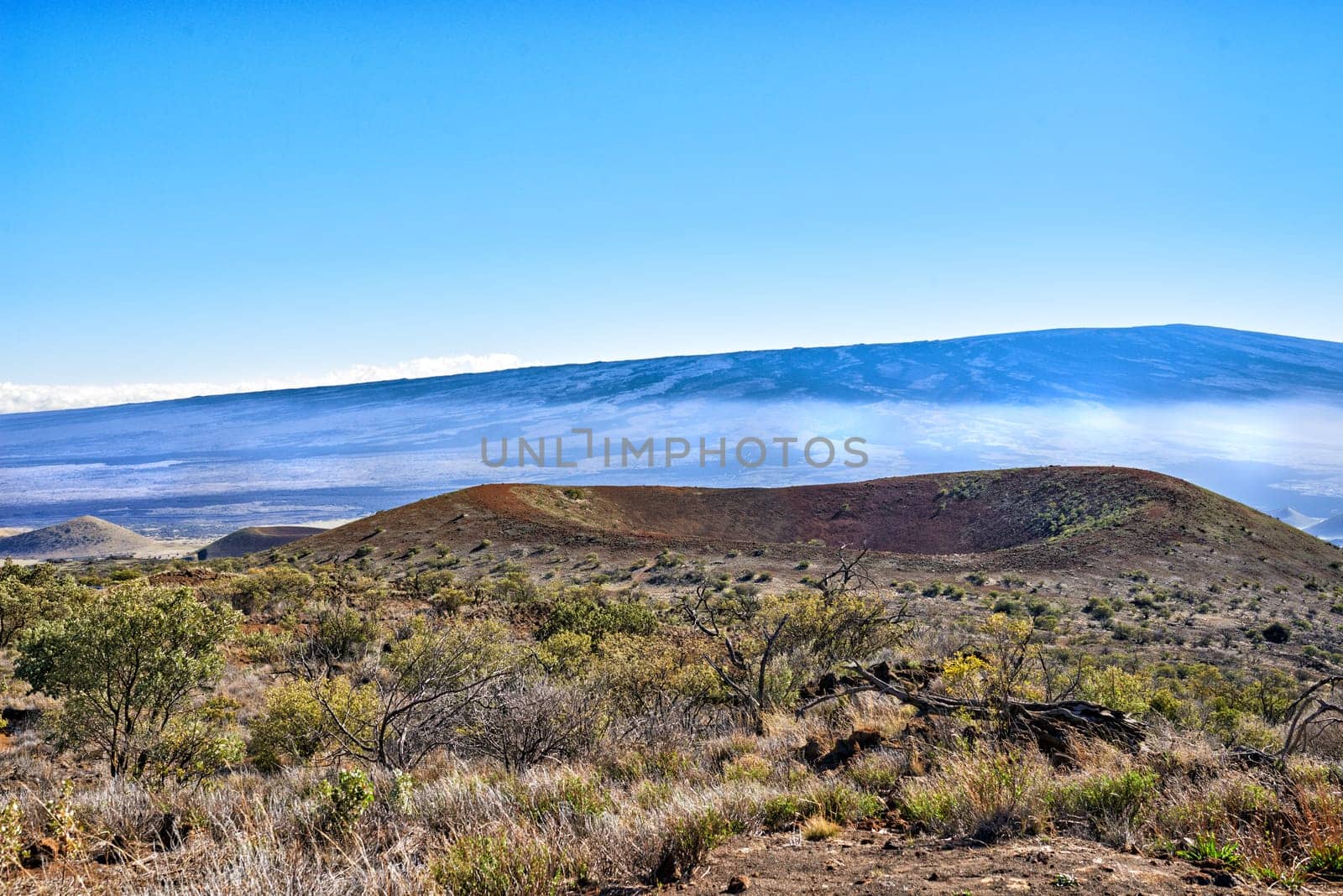 Hill, crater and landscape of mountain in countryside or morning fog on inactive volcano in Hawaii. Nature, horizon and travel to bush in valley with grass, plants and summer mist in blue sky by YuriArcurs