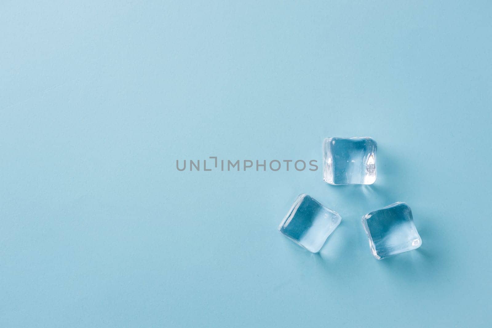 top view of ice cubes of different sizes on blue background by Sonat
