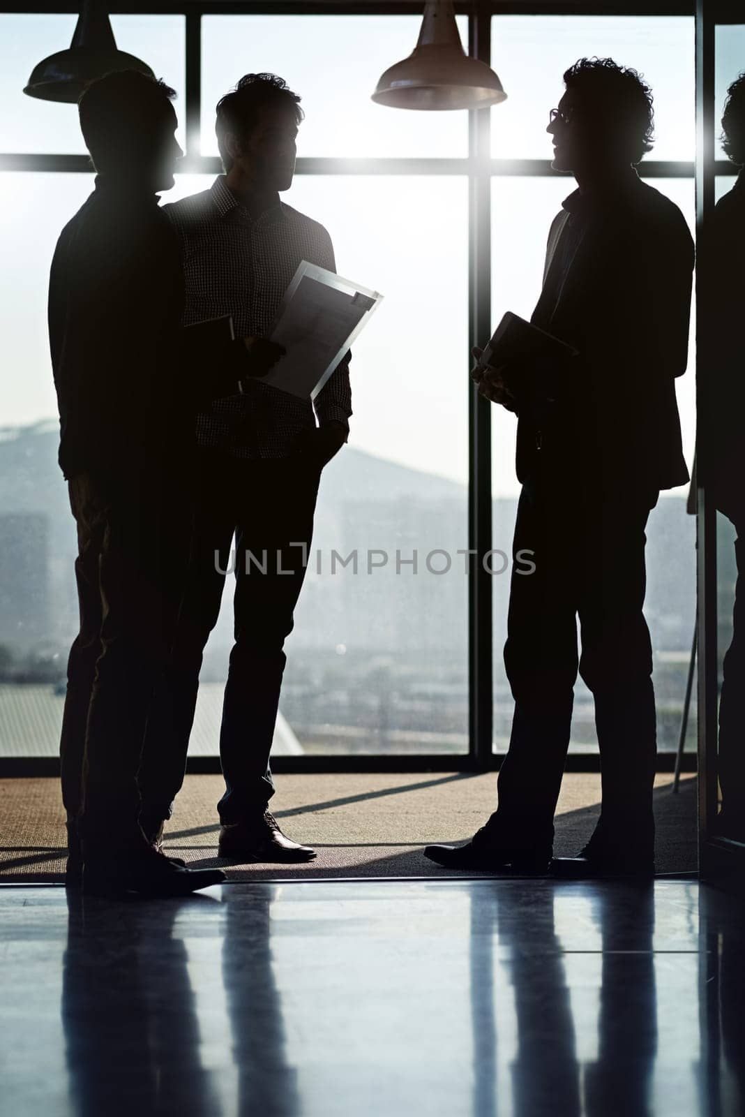 Businessman, silhouette and meeting by window in office with documents by talking or planning with partners for project strategy. Team, men and workshop or conference for ideas on company development by YuriArcurs