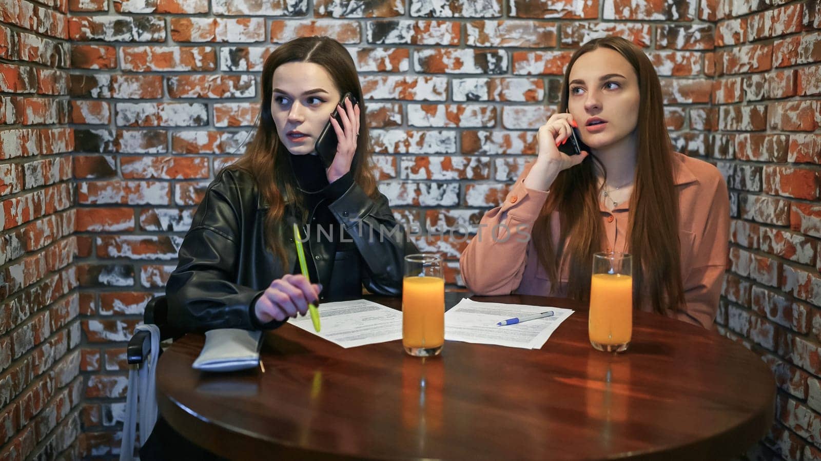 girls talking on their cell phones in a cafe. by DovidPro