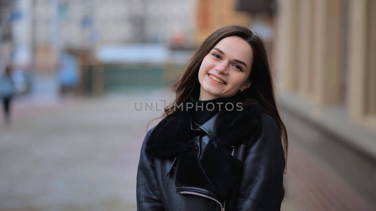 Happy brunette girl posing in black jacket in autumn in the city. by DovidPro