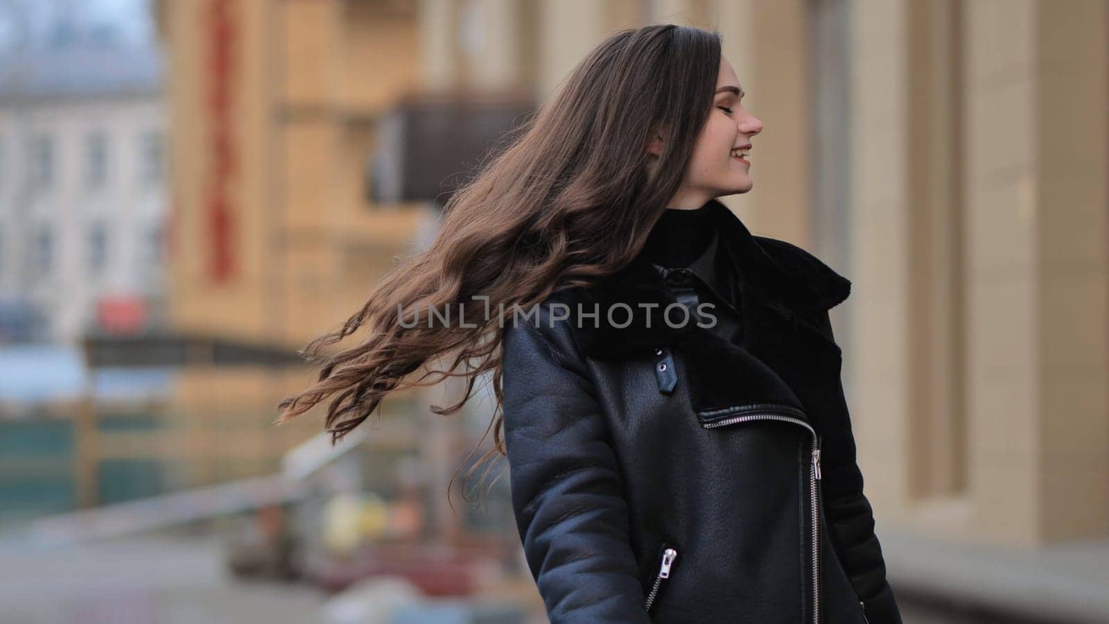 Happy brunette girl posing in black jacket in autumn in the city. by DovidPro