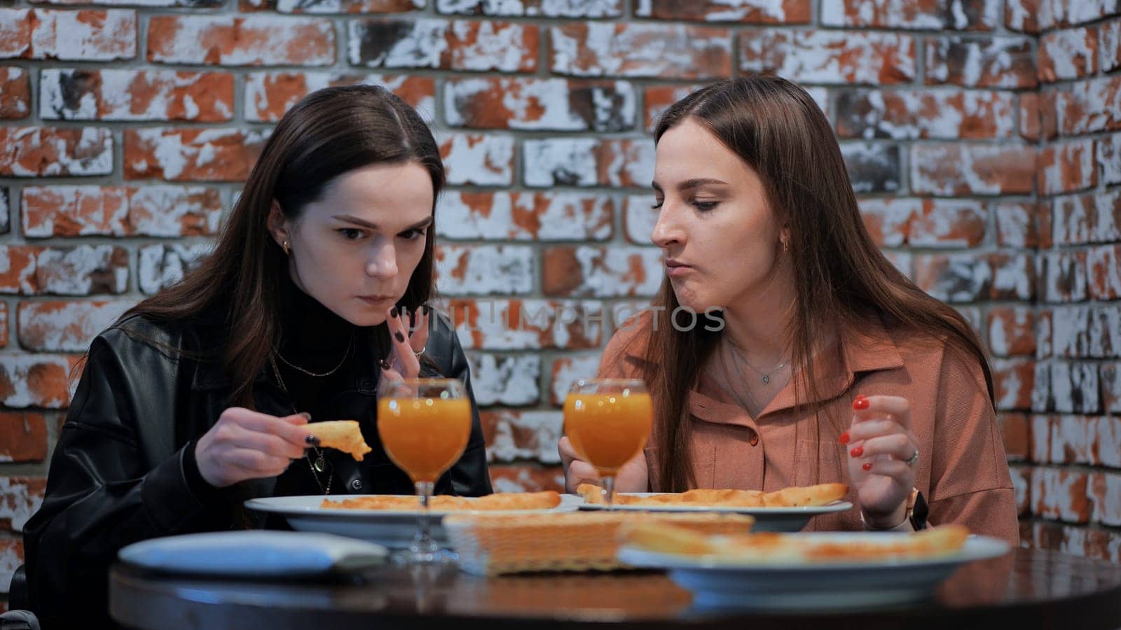 Two cheerful girls in a cafe having dinner. by DovidPro