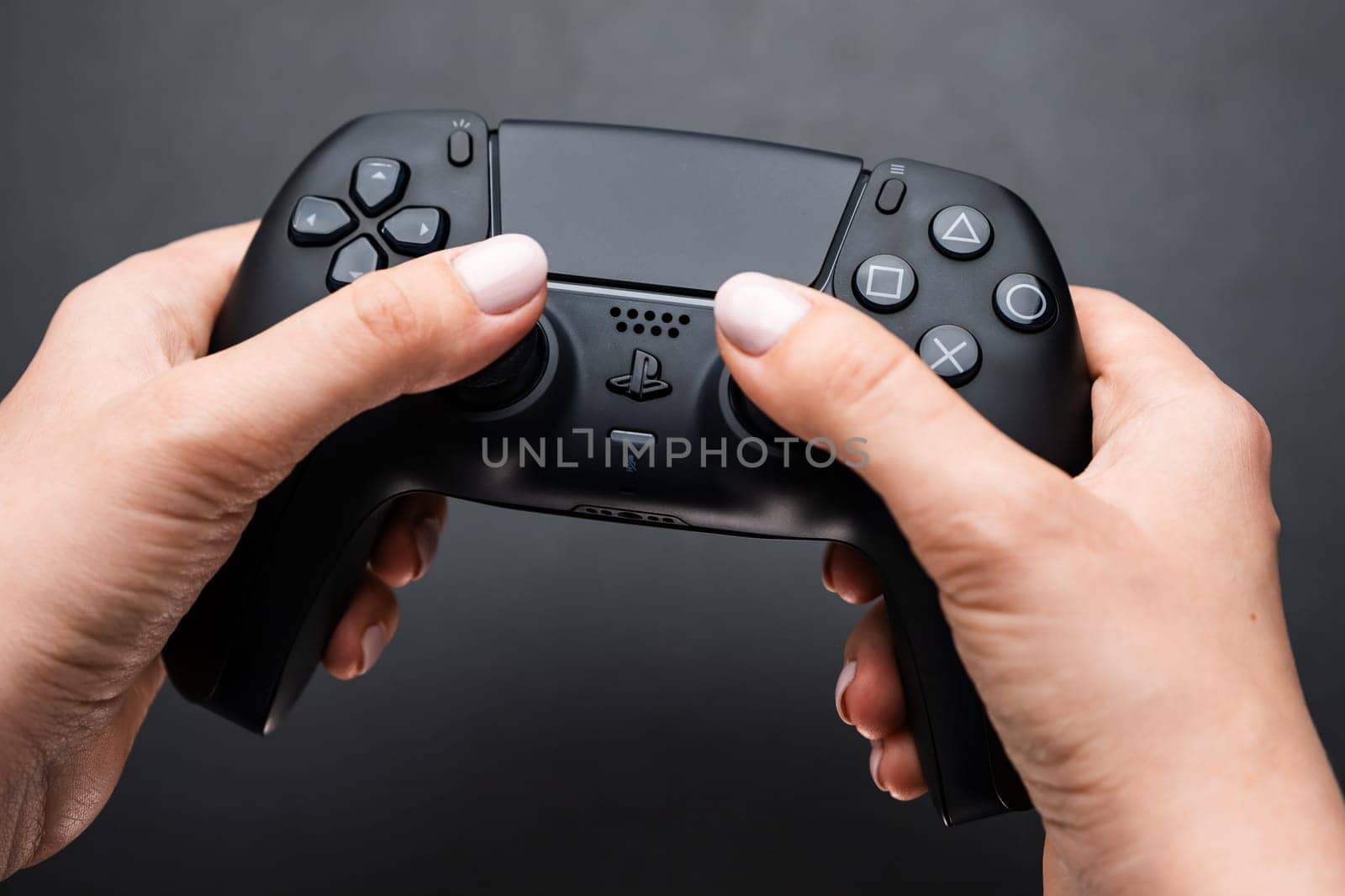 BERLIN , GERMANY - FEBRUARY 14 2024: Video game controller in womans hand on the black ground.