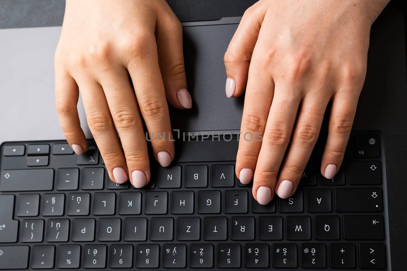 BERLIN, GERMANY - APRIL 14 2024: Top view female hand working on a laptop keyboard. Business office workplace concept.