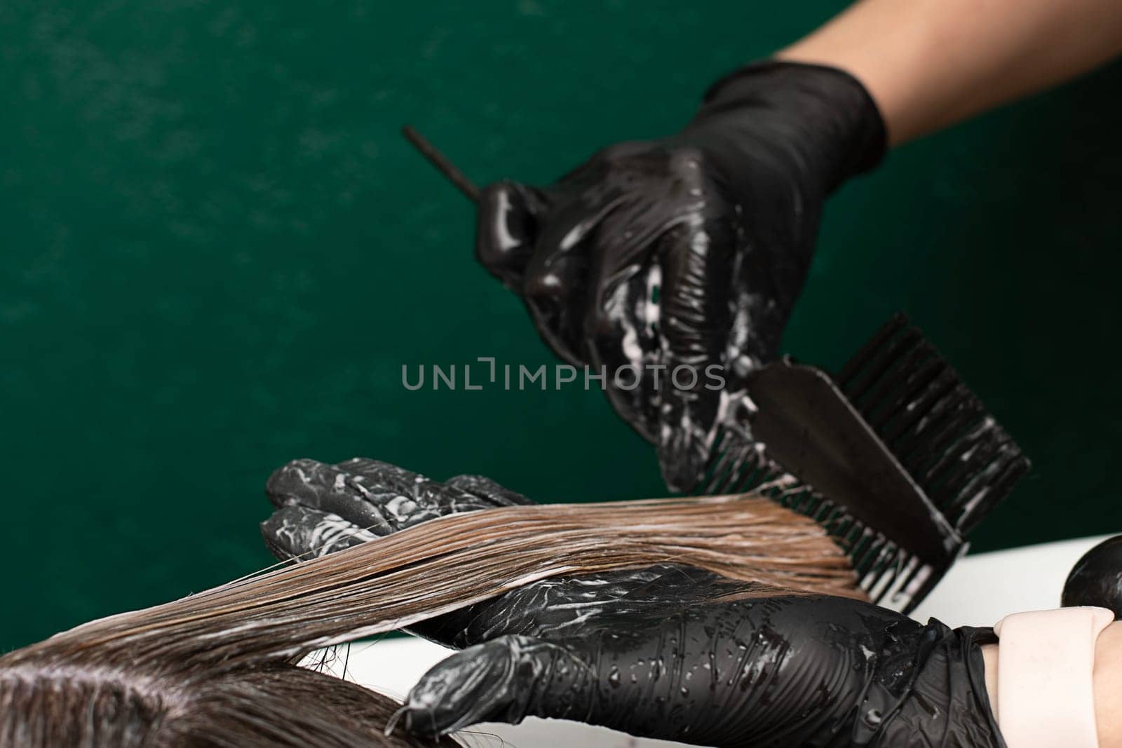 Beauty sphere. Hair coloring in a beauty salon. A master hairdresser-colorist combs long hair with a comb and brush and washes it with shampoo in a hair washer. Close-up. Business concept. No faces.