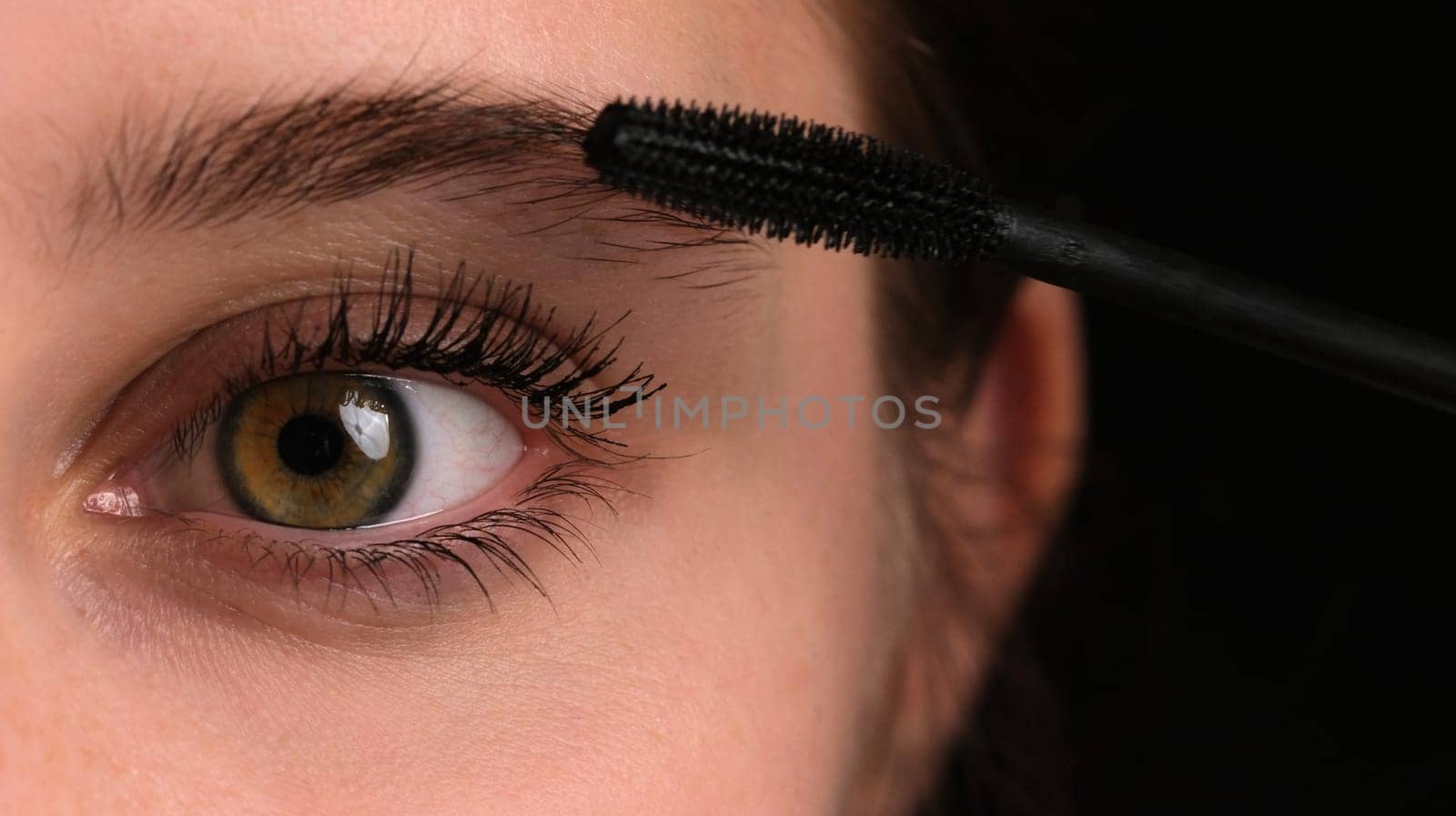 Girl Seen Up Close Applying Black Mascara To Her Long Eyelashes