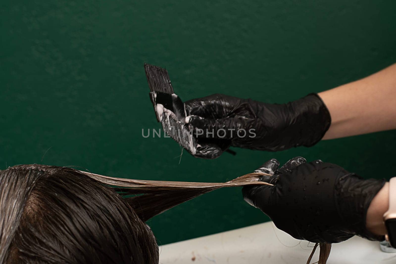 Beauty sphere. Hair coloring in a beauty salon. A master hairdresser-colorist combs long hair with a comb and brush and washes it with shampoo in a hair washer. Close-up. Business concept. by ketlit