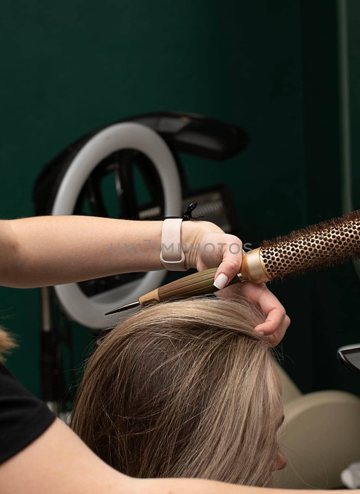 Beauty sphere. The master hairdresser does styling and combing the hair. Combs a client's long hair with a round brush and blow-dries it in a beauty salon. Close-up. Business concept. No faces.