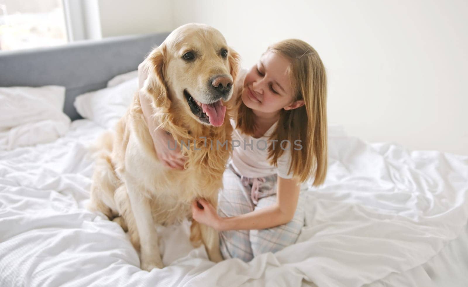 Sweet Little Girl Embracing A Lovely Golden Retriever Dog On A Bed In The Morning