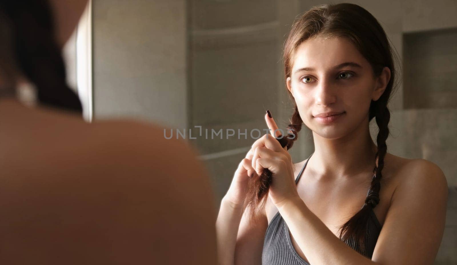 Adolescent Girl Brushing And Braiding Her Hair In The Mirror In The Morning Routine by GekaSkr