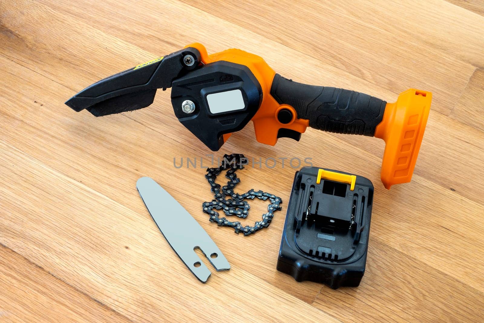 metal chain, bar and small accumulator chainsaw to trim broken branches of a tree 