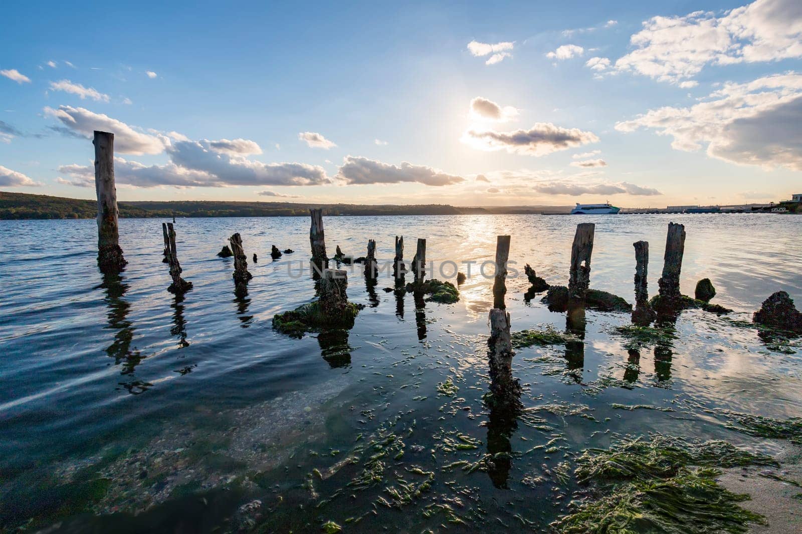 Old timber pillars protruding from the water against the sunset sky