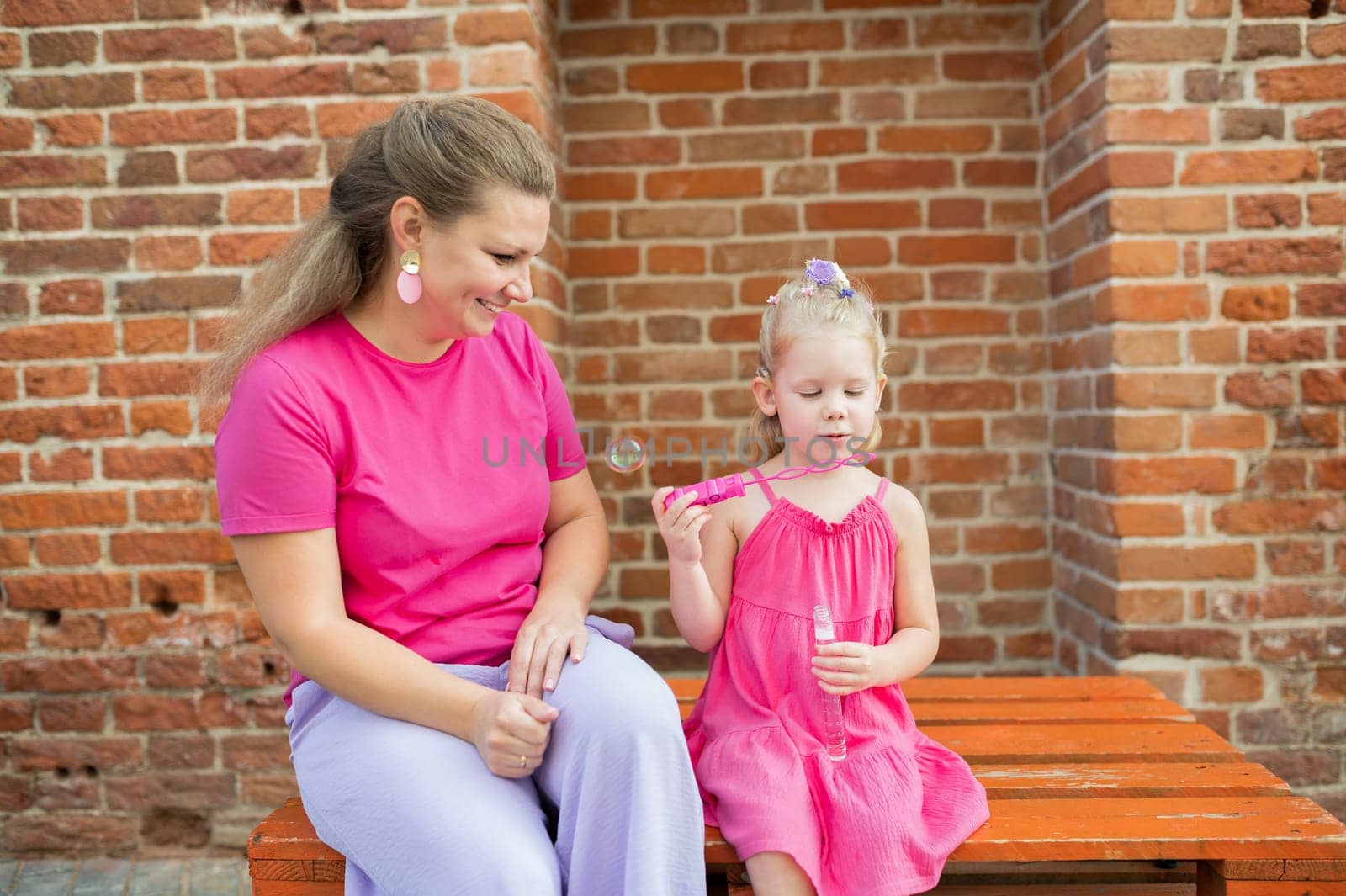 Blonde little girl with cochlear implant playing with her mother outdoor. Hear impairment deaf and health concept. Disability and inclusion. Copy space by Satura86