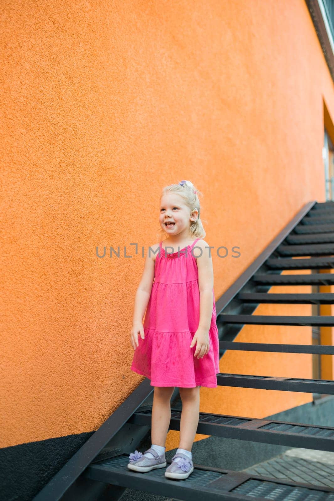 Child girl walks and have fun outdoor with cochlear implant on the head. Hearing aid and treatment concept. Copy space vertical.