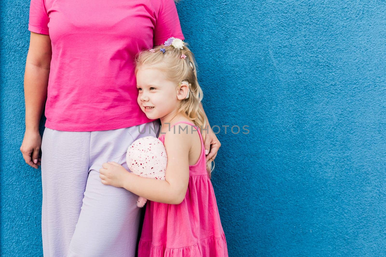 Child girl with cochlear implant with her mother spend time outdoor. Hear impairment and deaf community concept. Deaf and health concept. Diversity and inclusion. Copy space.