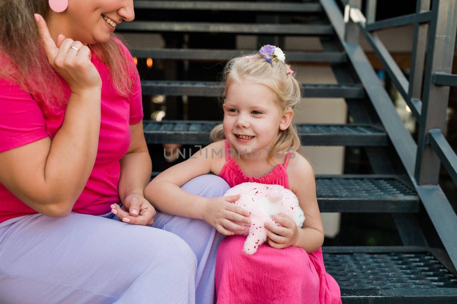 Deaf child with cochlear implant for hearing audio and aid for impairment having fun and laughs with mother outdoor in summer. Sound fitting device to help with communication listening and interaction.