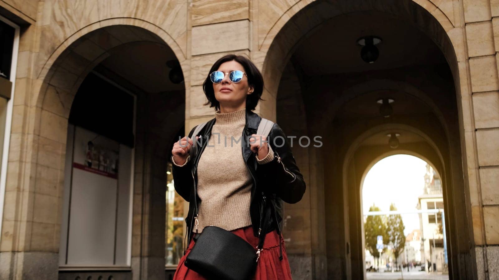 Attractive Woman In Sunglasses Walks In City With Backpack, Female Tourist Looking Around