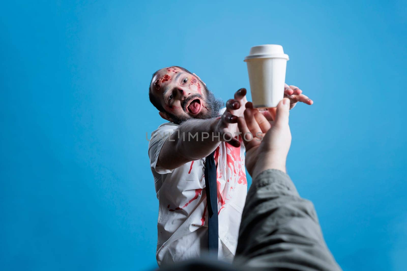 Man can't function without coffee, trying to grab cup, studio background by DCStudio