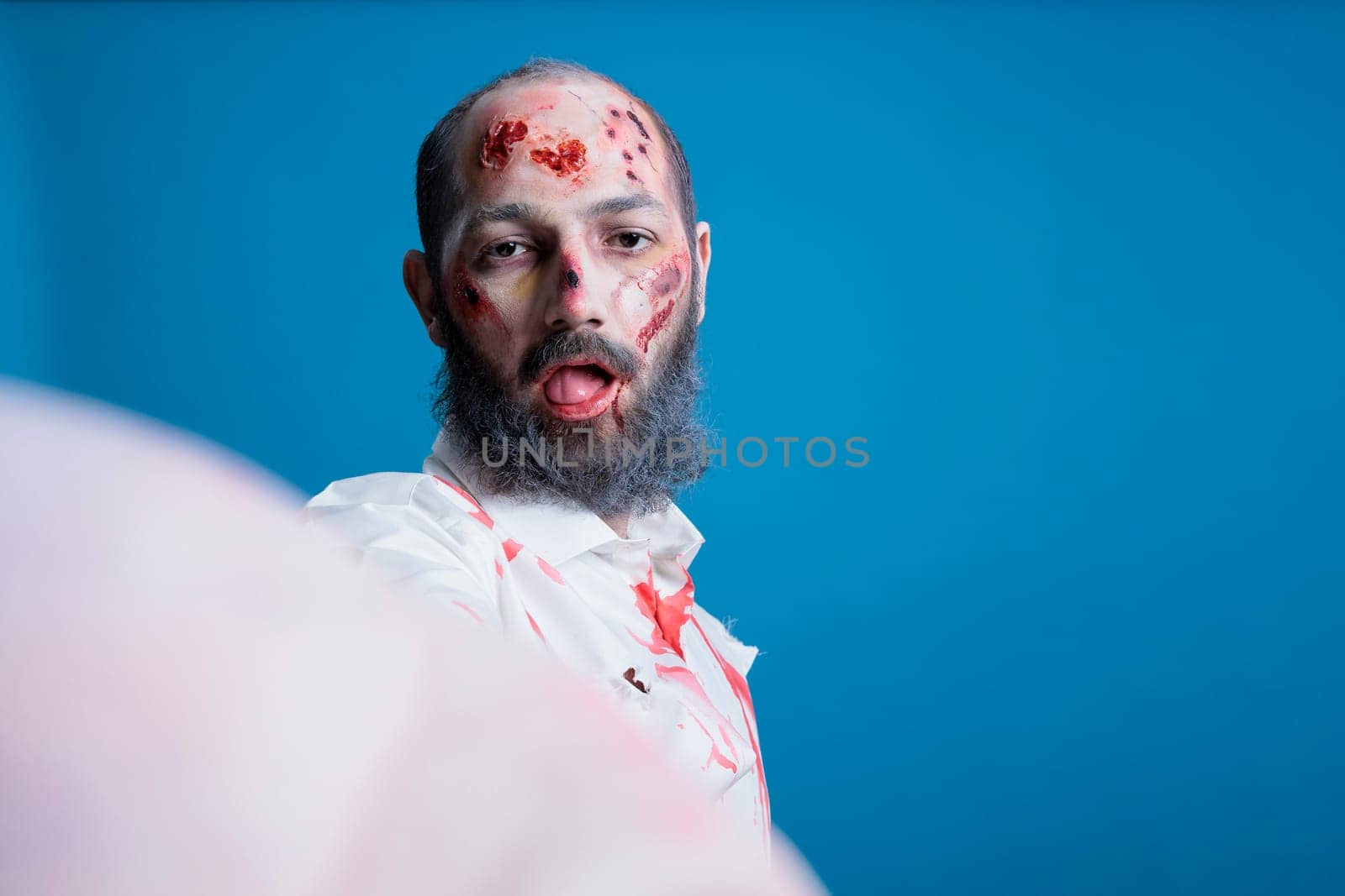 Portrait of brainless zombie isolated over studio background doing selfies by DCStudio