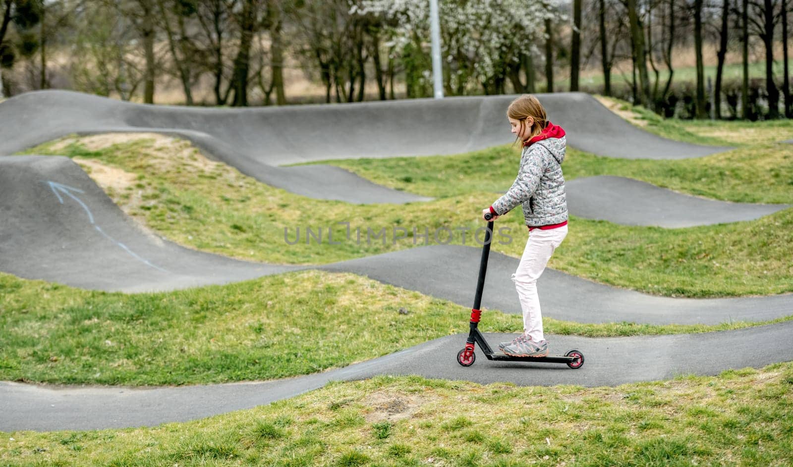 Beautiful little girl rides a scooter in a ride park by GekaSkr