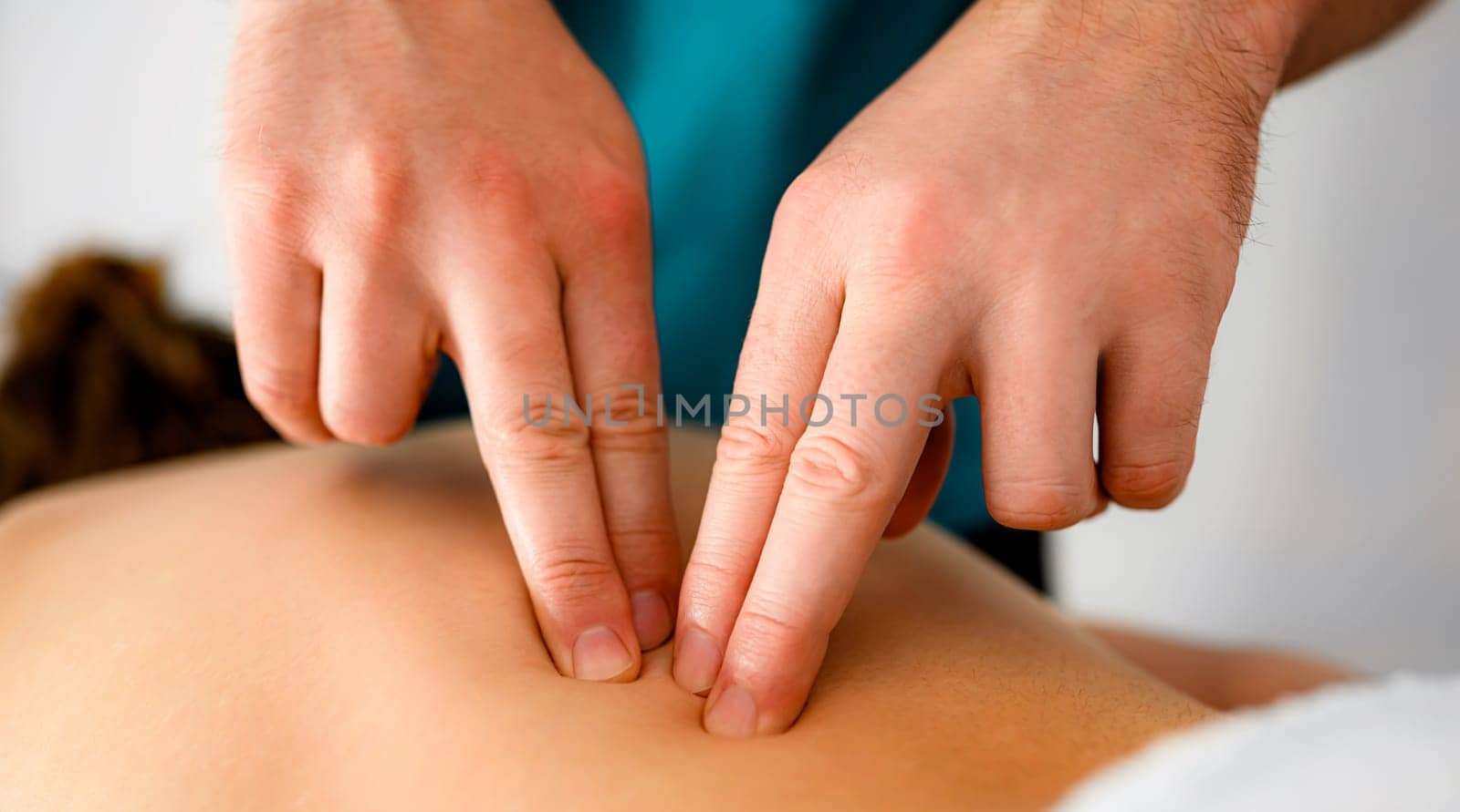 Masseur making back massage with fingers to girl client closeup. Body care treatment therapy procedure for wellness and relaxation in spa salon clinic.