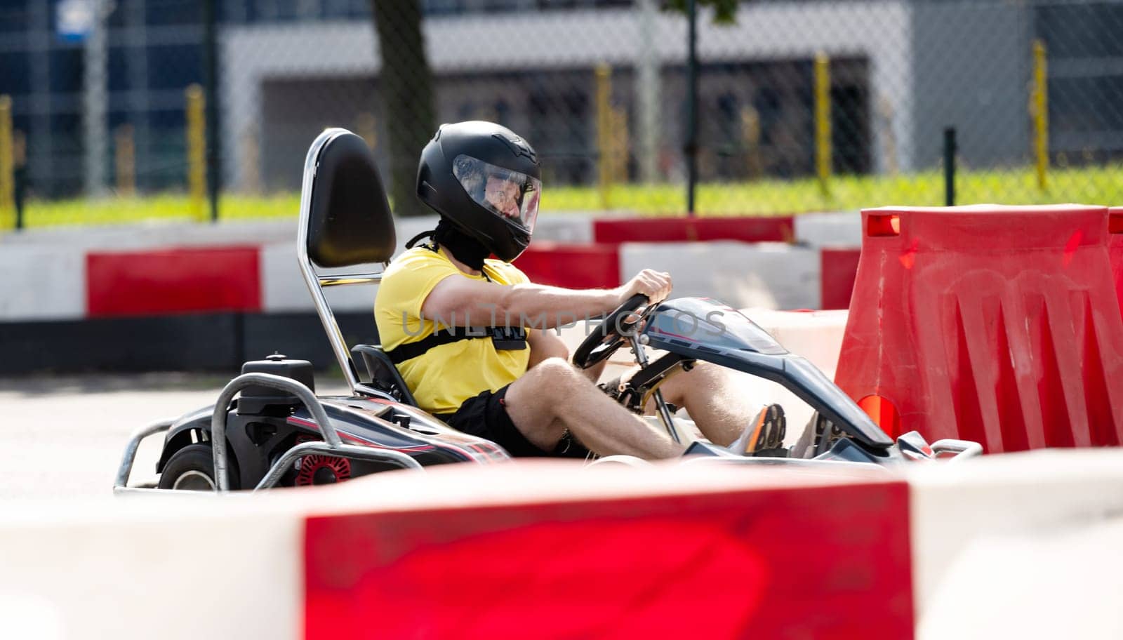 Man In Protective Helmet Driving Go-Kart By Racing Track by GekaSkr