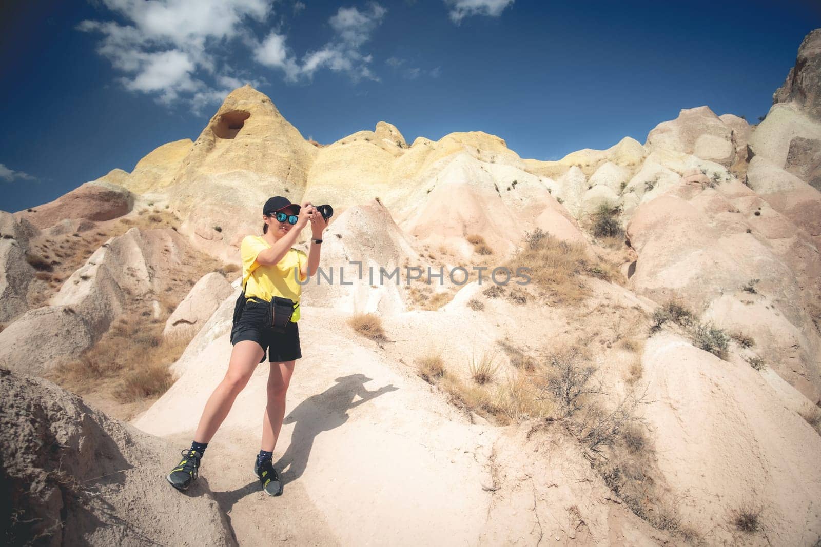 Woman with camera standing on mountain hill in Cappadocia, Turkey