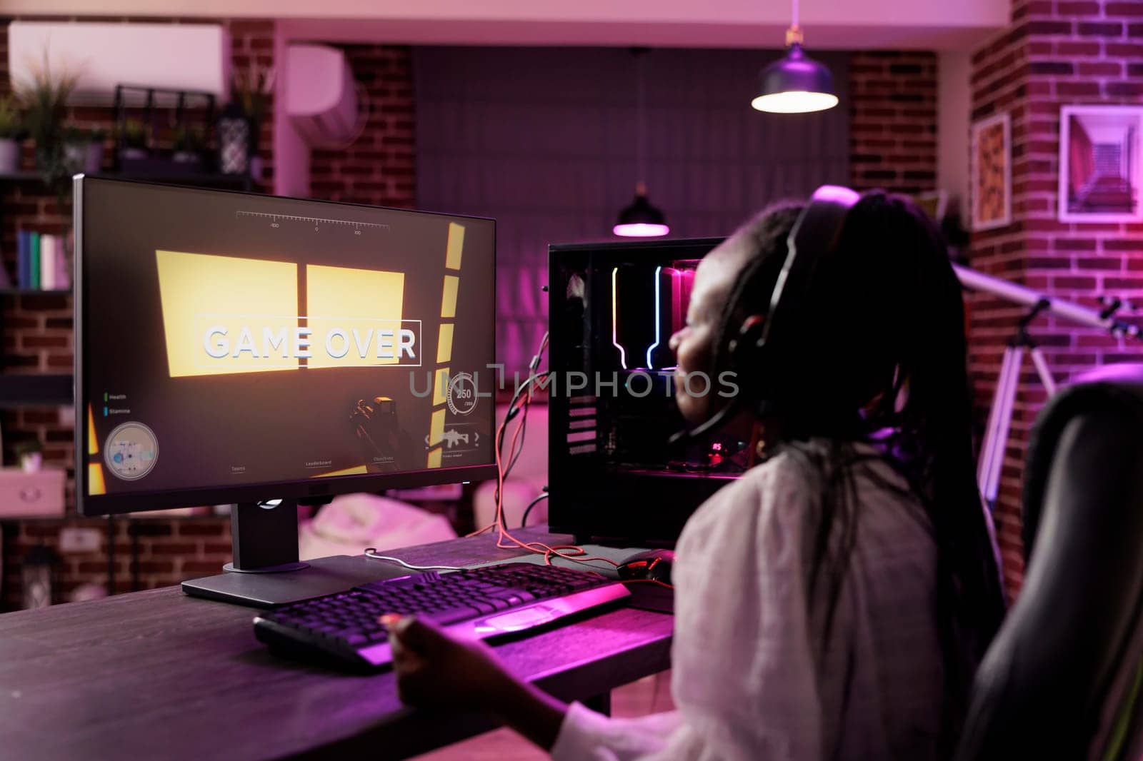 Content creator playing online multiplayer videogame on gaming PC, losing in live esports tournament. African american pro gamer defeated while streaming game for audience watching from home