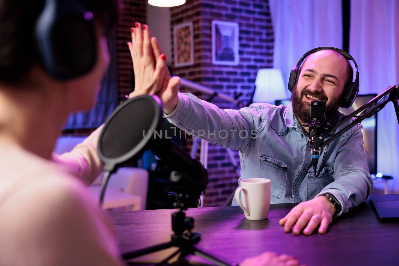 Show host interviewing woman during live stream, talking about fashion and style trends, agreeing with her opinions. Man high fiving social media content creator, recording podcast