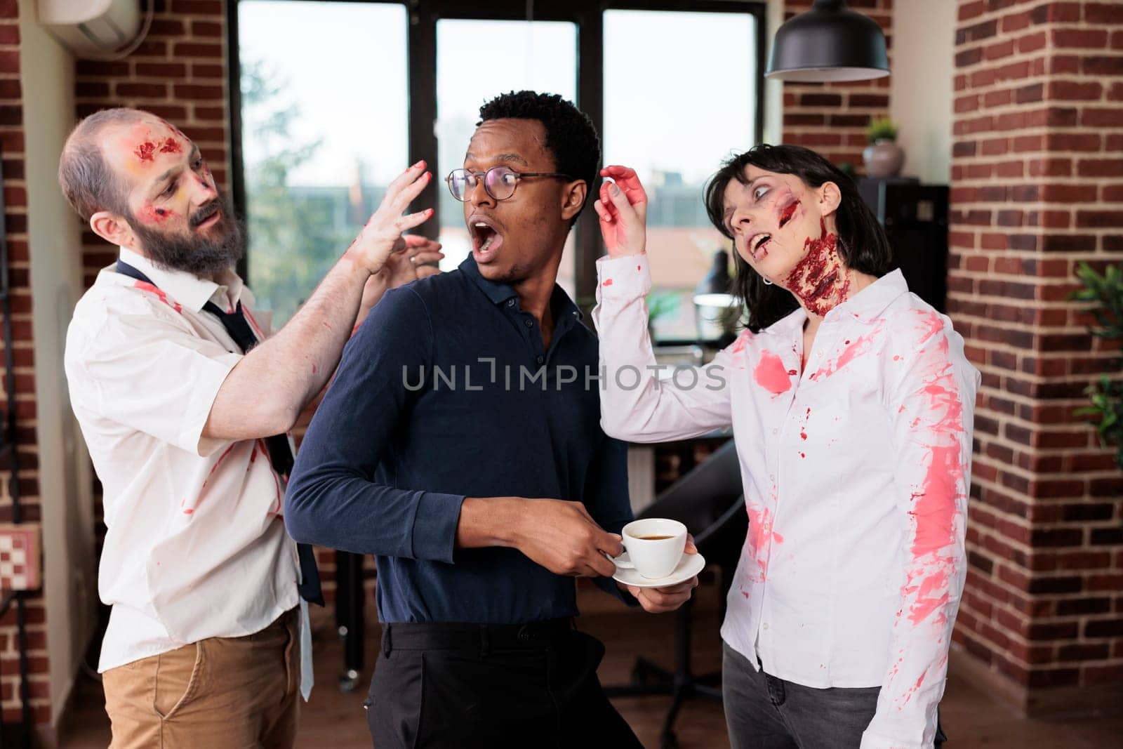 Team leader and workers dressed as zombies having fun during Halloween by DCStudio