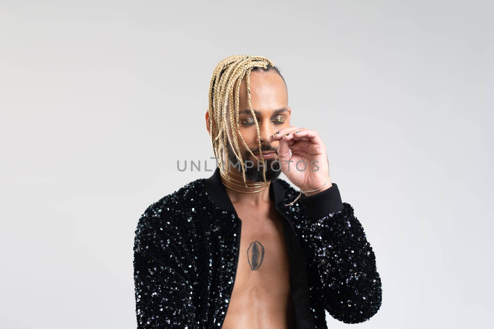 Man wearing stylish jacket with sequins on naked body. Afro-american homosexual male posing in photo studio on white background. Bearded gay with beard and make up