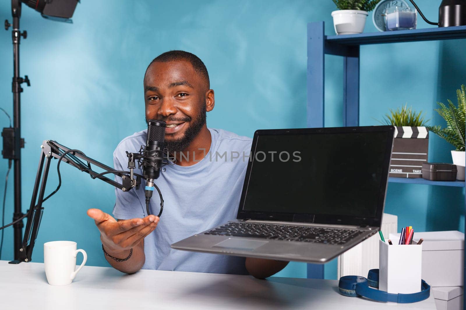 Smiling social media influencer promoting laptop while recording video for social media. African american streamer advertising portable computer while live broadcasting and looking at camera