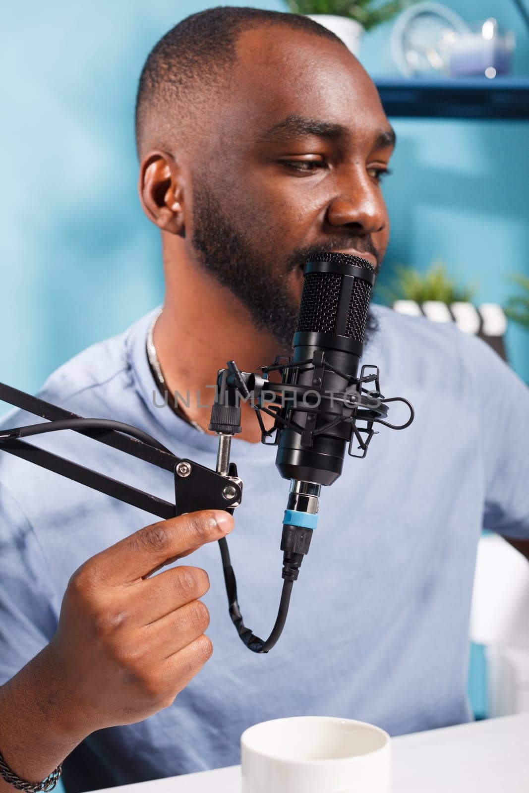 African american vlogger speaking in microphone on internet podcast channel. Young man blogger talking with subscribers in mic while broadcasting live and creating web content in studio