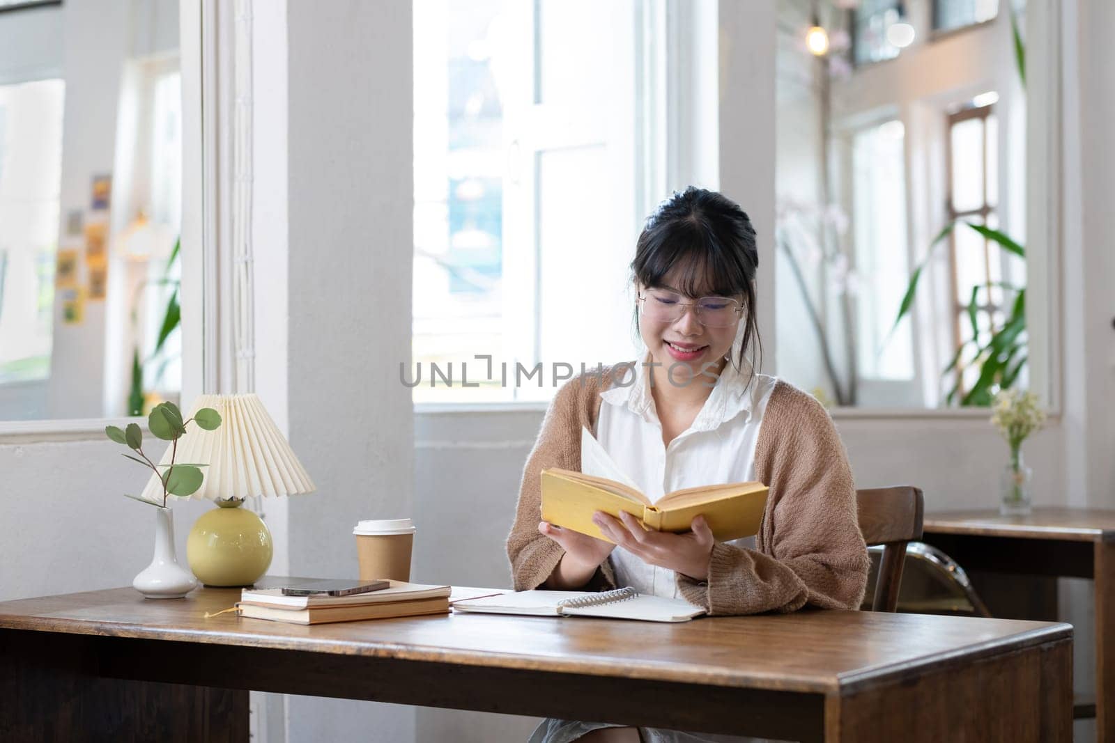 Asian students study online, take notes, do homework, study online from home on a wooden table in the house..