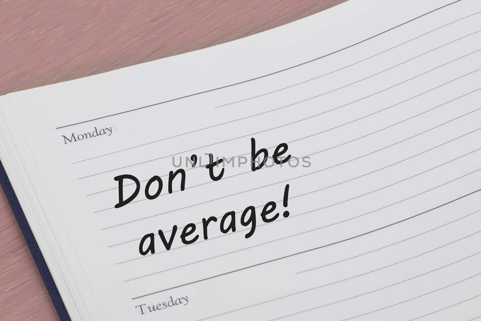 Dont be average diary reminder open on a desk by VivacityImages
