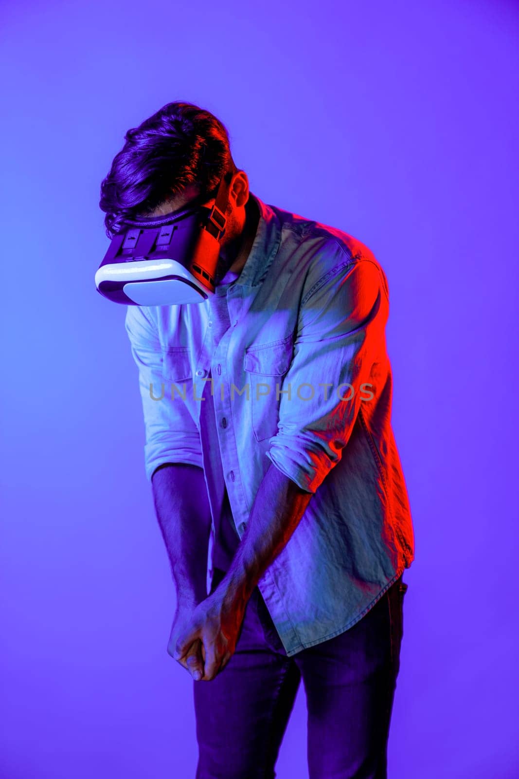 Man moving in golf playing gesture while standing at neon background. Deviation. by biancoblue