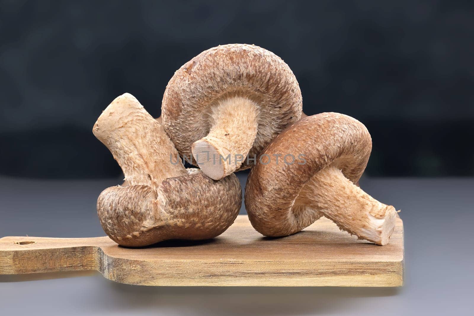 Shiitake mushrooms on cutting board over dark background by NetPix