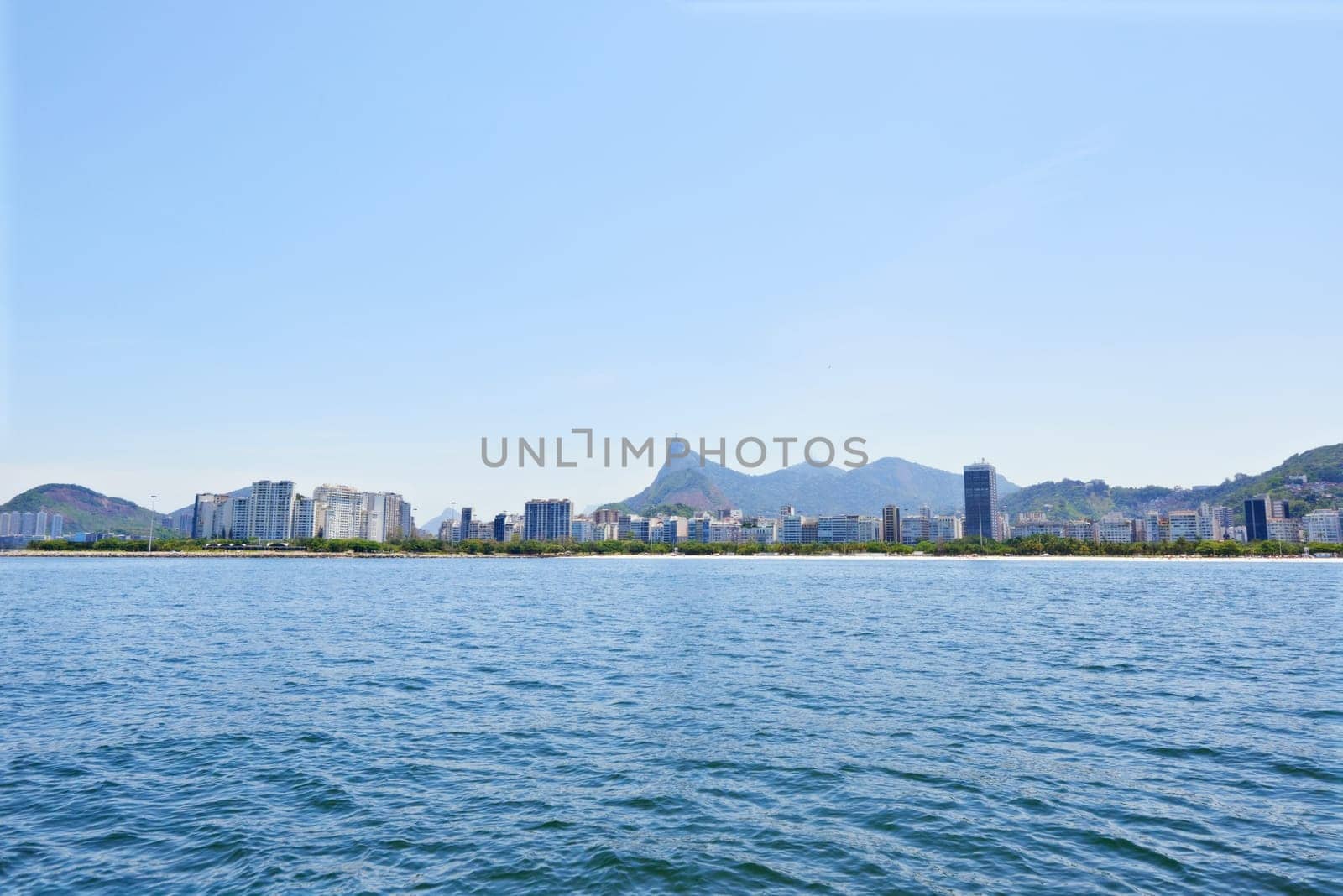 Water, ocean and city with nature, blue sky and vacation with getaway trip, Rio de Janeiro and adventure. Beach, aerial view and outdoor with mountains, sunshine and summer with holiday and travel.