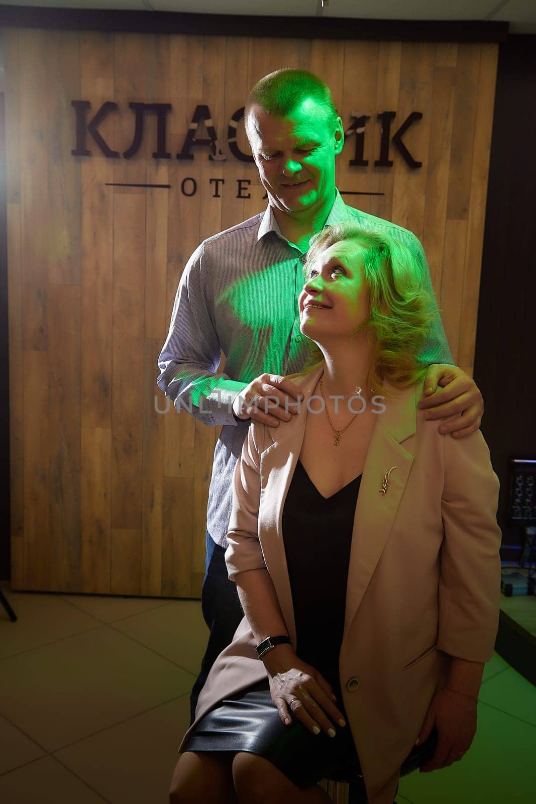 Adult man and woman are conversing on stage in dimly lit room before a performance or interview. The actors, actress, host, journalist, and paparazzi capturing their intimate, secretive conversation