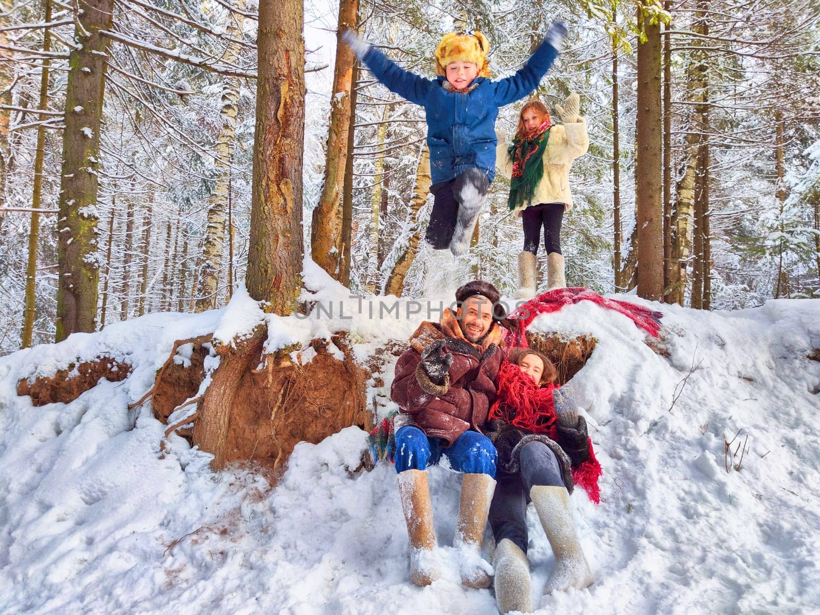 Joyful family ethnic dress with shawls and earflap hats in a winter forest in carnival Maslenitsa in Russia. Tourists in Shrovetide in spring. Mother, father, son, daughter having fun in the snow by keleny