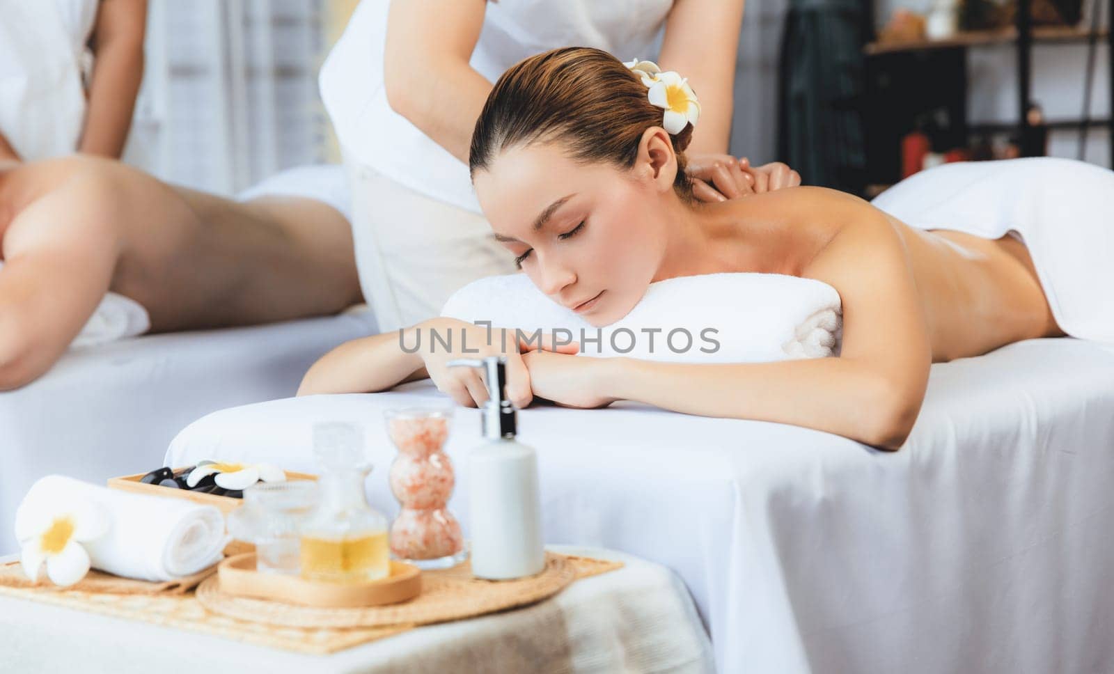 Caucasian couple customer enjoying relaxing anti-stress spa massage and pampering with beauty skin recreation leisure in day light ambient salon spa at luxury resort or hotel. Quiescent