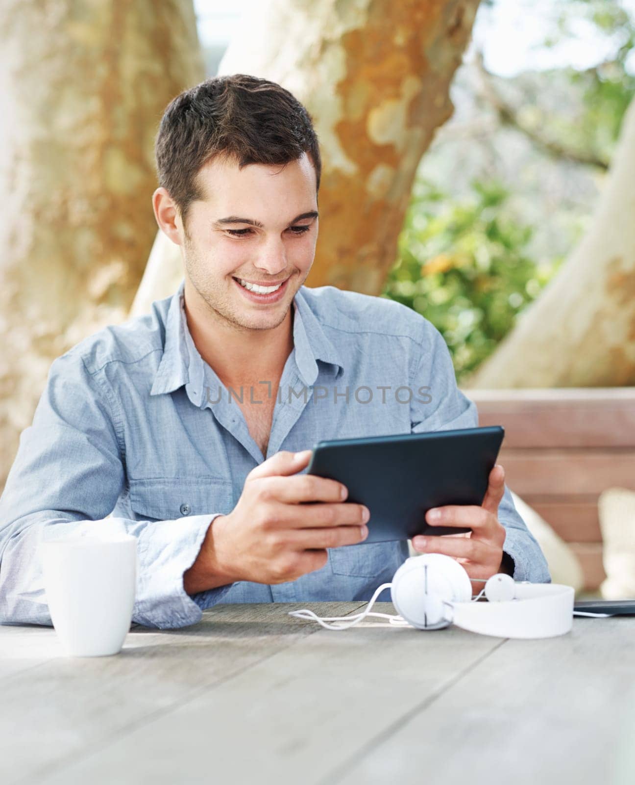 Smile, park and man with tablet in nature on table for networking, email and freelance job. Happy, digital nomad and graphic designer with tech in garden for creative research, feedback and review.