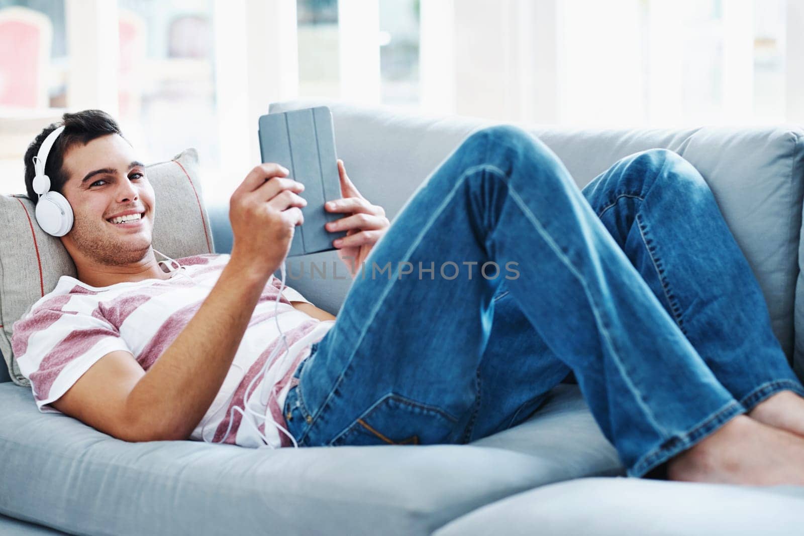 Sofa, headphones and portrait of man with tablet for online video, subscription and watching movie. Happy, relax and male person with digital technology at home for network, connectivity or streaming.