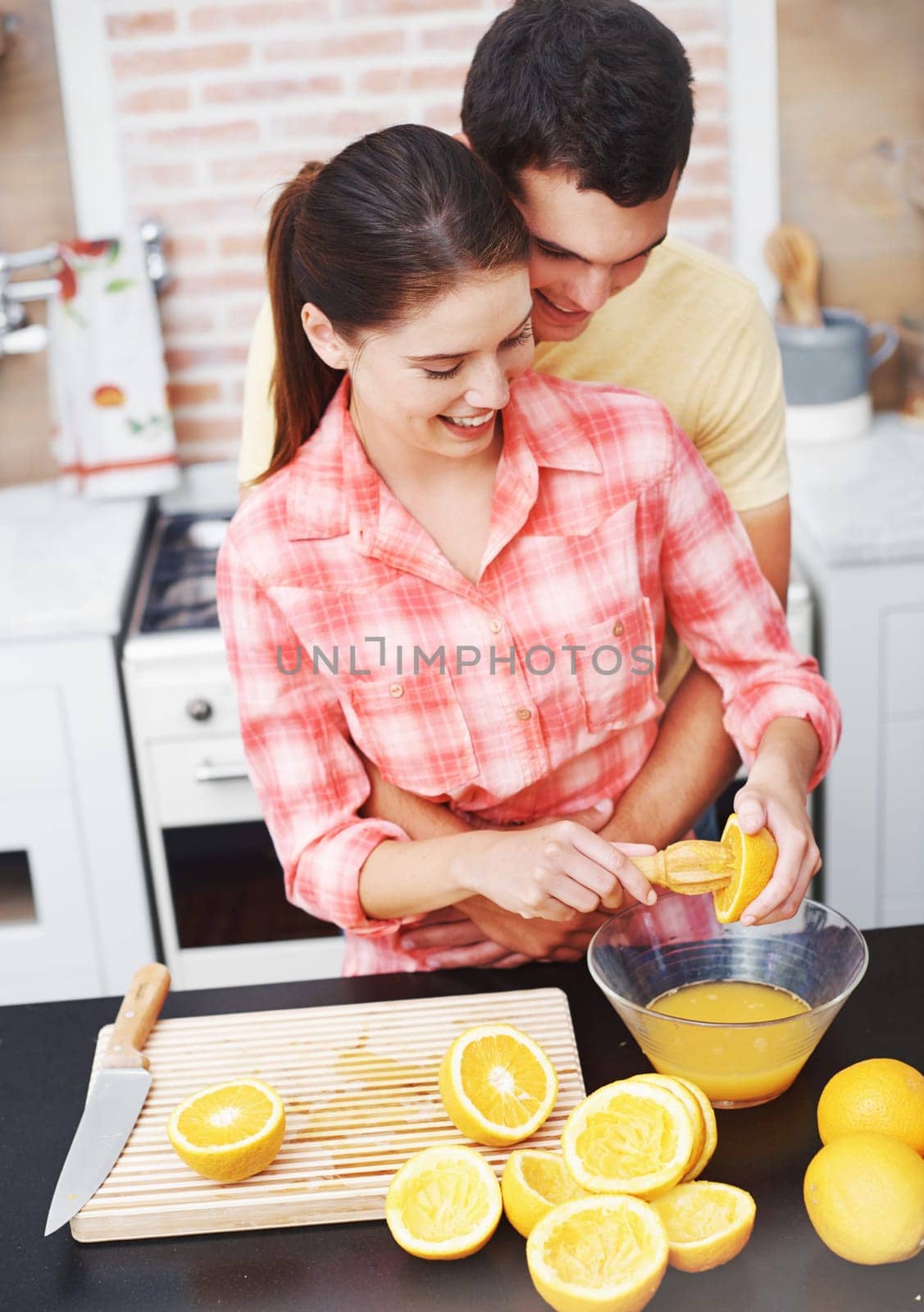 Couple, kitchen and happy with orange for juice in bowl for health, nutrition and diet with ingredients. Home, relationship and bonding with fruit for sweet flavor or lunch snack and fresh food.