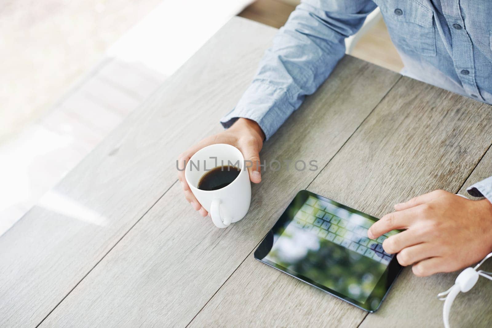 Sun, coffee and hand with tablet on desk for communication, online search and connectivity. Man, high angle and morning with digital technology on table for internet, networking and social media by YuriArcurs