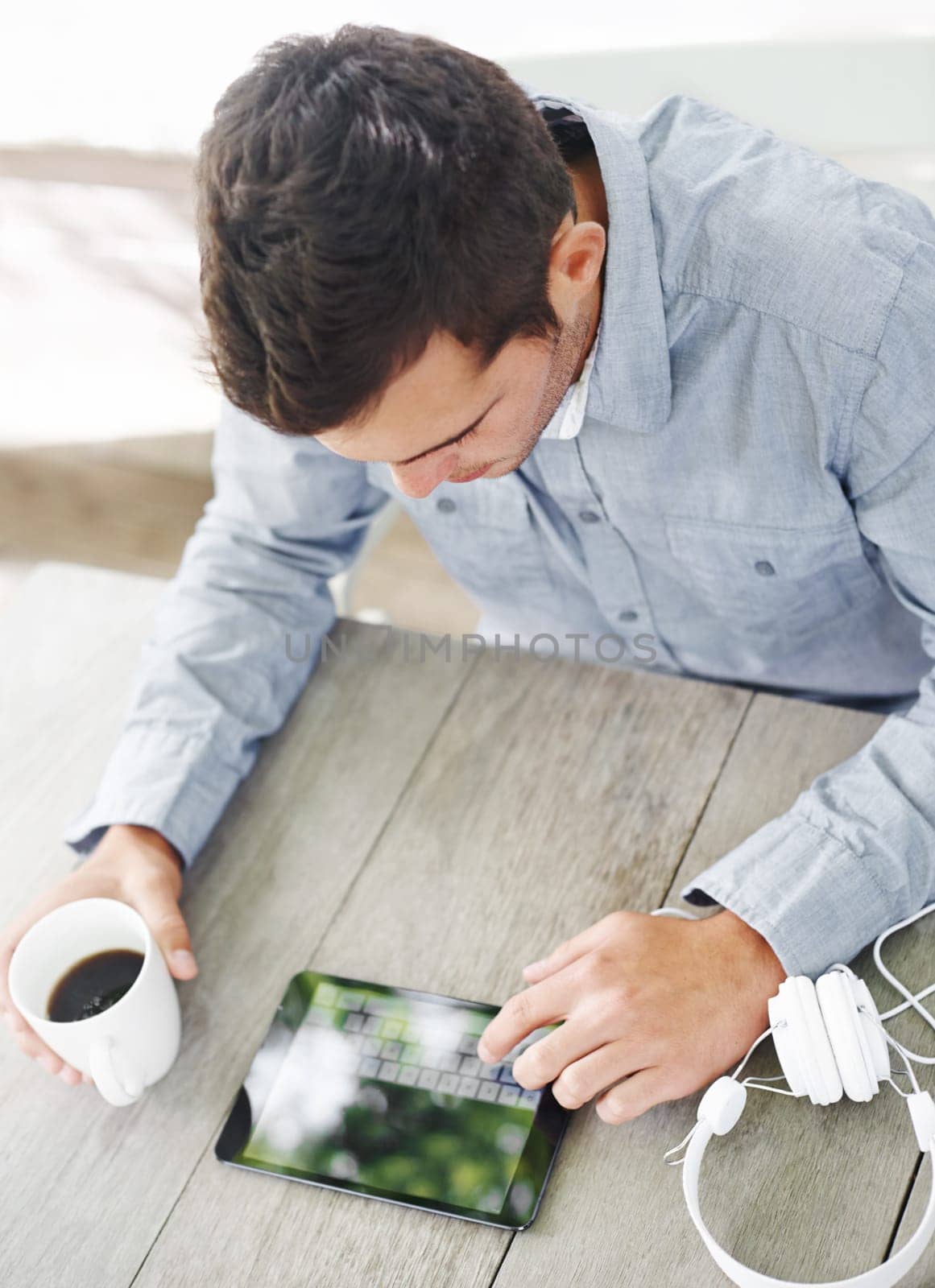 Desk, coffee and man with typing on tablet for communication, connectivity and networking. Morning, contact and male person with digital technology on table for online blog, website and research.