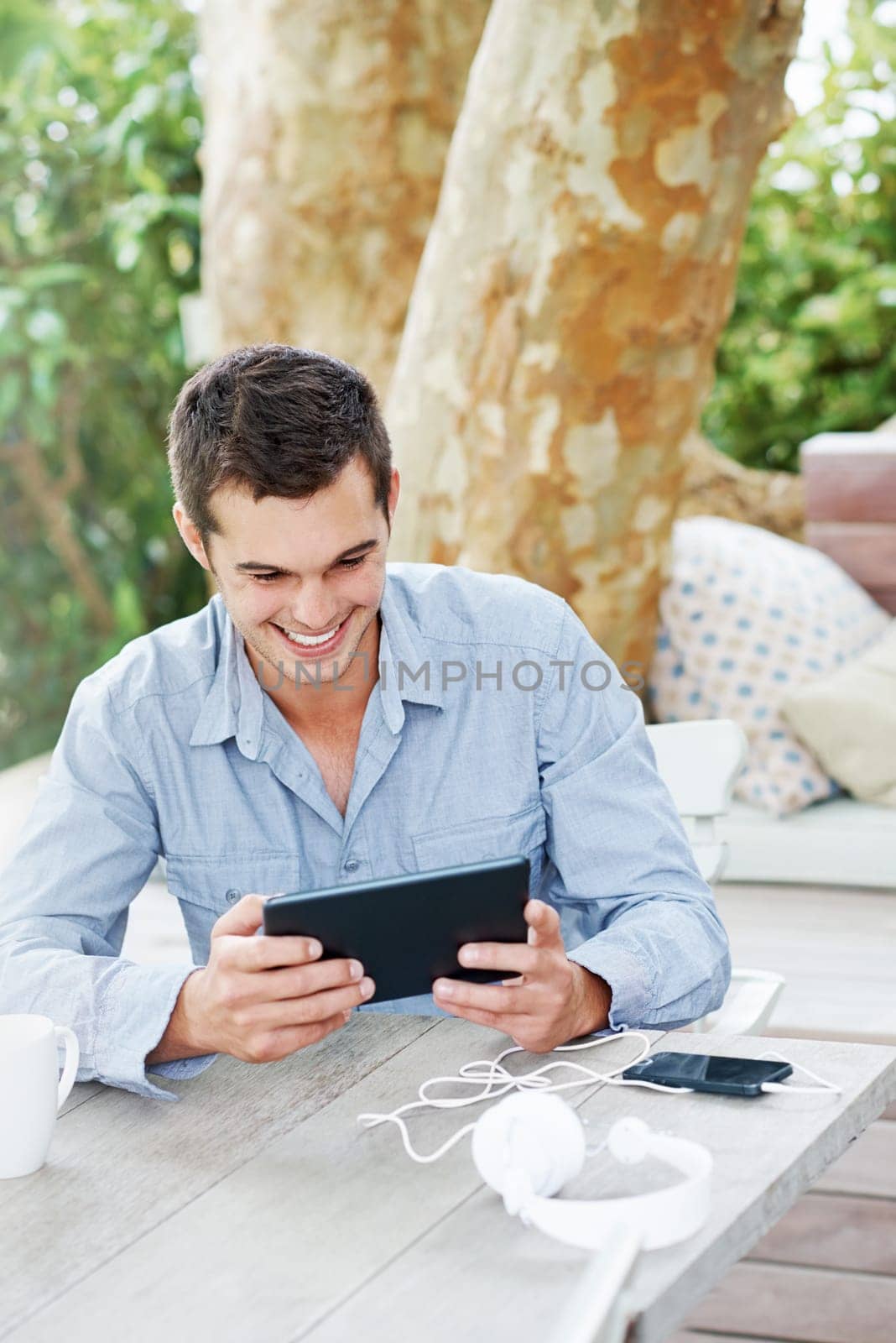 Internet, smile and man with tablet on patio for networking, communication and social media. Happy, male person and desk with technology in garden for online search, digital streaming or information.