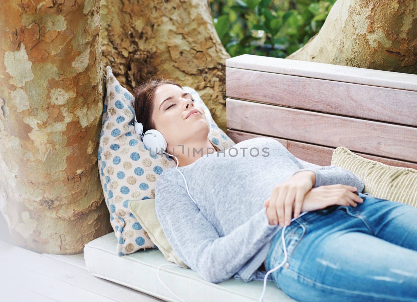 Above, woman and sleeping with headphones for streaming on cellphone for music, podcast or audio on couch. Female person, smile and comfort at home in outdoor in relaxing, free and peaceful with tech.