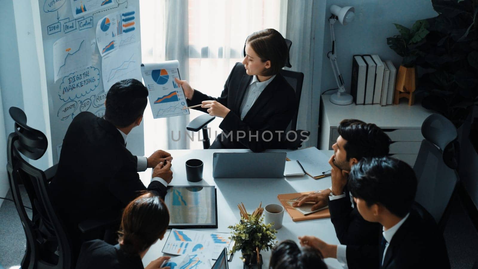 Top view of smart manager compare chart between board and paper while planning startup project with group of diverse team at business meeting. Team brainstorming and working together. Directorate.